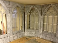 an unfinished room with stone walls and arched windows