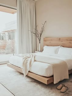 a bed with white sheets and pillows in a bedroom next to a window that looks out onto the backyard