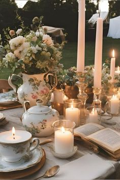 a table set with candles, tea cups and books for an outdoor dinner party in the garden