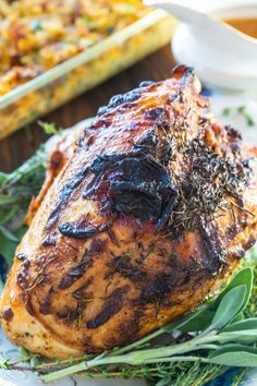 a close up of a chicken on a plate with herbs and sauces in the background