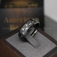 a black and white ring with birds on it in a wooden box next to a book