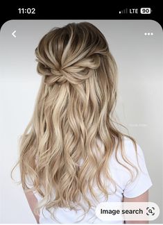 the back of a woman's head with long blonde hair styled into a half - updo