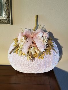 a white basket with pink and gold flowers in it sitting on a table next to a mirror