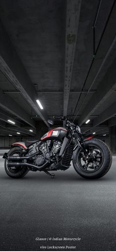 a red and black motorcycle is parked in a parking garage with its lights turned on