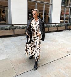 a woman in a leopard print dress is walking down the street