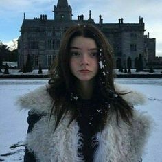 a woman standing in front of a large building with snow on it's roof