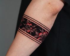 a woman's arm with a tattoo on it that has red flowers and black stripes