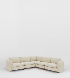 a white sectional couch with wooden legs