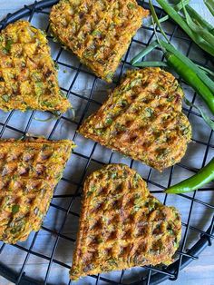 four waffles sitting on top of a wire rack next to green beans and peppers