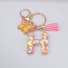 the letter h is decorated with multicolored confetti and a pink tassel