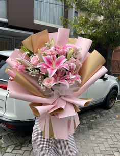 a person holding a bouquet of flowers in front of a car parked on the street