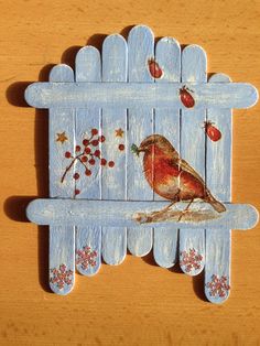 a wooden fence with a bird painted on it's side and berries in the background