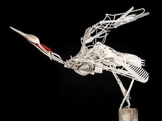 a sculpture made out of wire with a toothbrush in it's mouth and an arrow sticking out of the side