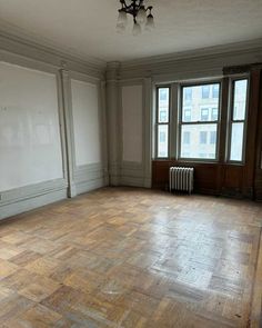 an empty room with hard wood flooring and large windows in the wall to the right