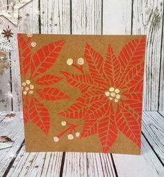 an orange and brown christmas card with gold foil on the front, featuring poinsettia leaves