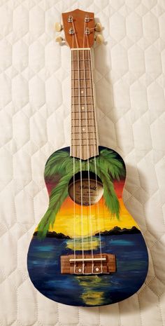 the ukulele is painted with an image of a tropical sunset and palm trees