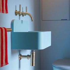 a blue sink and toilet in a small bathroom with red and white towels hanging on the wall