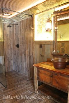 a bathroom with a sink, mirror and shower in it's stall area next to a wooden counter