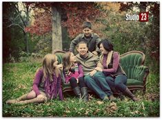 a group of people sitting on top of a green couch in the middle of a field