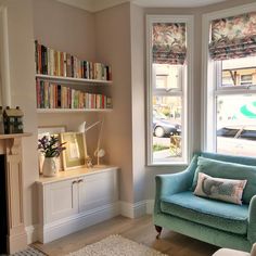 a living room filled with furniture and a fire place next to a window covered in books