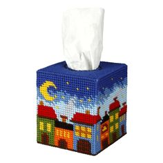 a blue tissue box with a night scene on it and a white paper towel hanging from the top