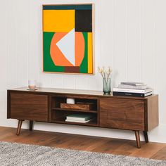 a painting hangs on the wall next to a wooden entertainment center with drawers and shelves