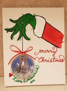 a christmas ornament hanging from the side of a tile wall with a hand holding a baby's head