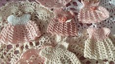 several crocheted baby hats and sweaters on a doily with pink flowers