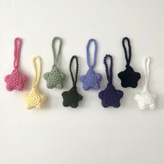 six crocheted items are arranged in a row on a white surface, one has a knot at the end