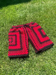 two red and black crocheted towels laying on the grass