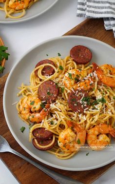 two plates of pasta with sausage and shrimp