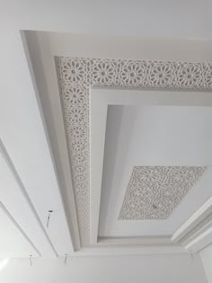 a room with white walls and ceiling tiles on the ceiling is decorated with intricate designs