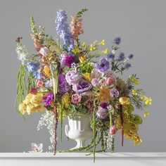 a white vase filled with lots of colorful flowers