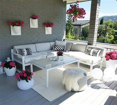 a white couch sitting on top of a wooden floor next to potted pink flowers