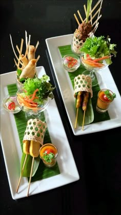 two white plates topped with food on top of green leaves covered in sauces and garnishes