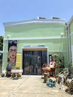 a green building with an advertisement on the front door and chairs in front of it