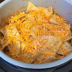 a bowl filled with nachos and cheese on top of a stove burner