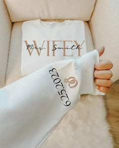 a woman's hand holding onto a white t - shirt with the word wifty on it