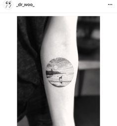 a black and white photo of a person's arm with a sunset tattoo on it