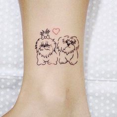 a small tattoo on the ankle of a woman's foot with two dogs and a heart