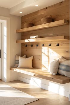 a room with wooden shelves and pillows on top of the shelf, in front of a door that leads to another room