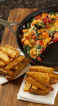 an omelet and french fries on a cutting board