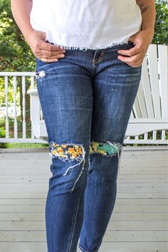 a woman in white shirt and jeans standing on porch with her hands behind her back