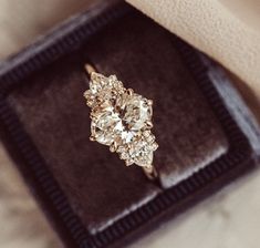 an old diamond ring sitting on top of a velvet box with its cover pulled back