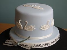 a birthday cake with two swans on it and a ribbon tied around the top that says happy birthday