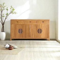 a wooden cabinet sitting on top of a hard wood floor next to a potted plant