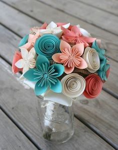 a vase filled with paper flowers on top of a wooden table