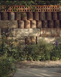 an old brick wall with many pots on it and flowers growing in the foreground