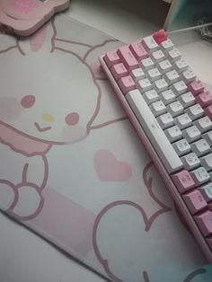 a pink and white keyboard sitting on top of a mouse pad next to a hello kitty mouse