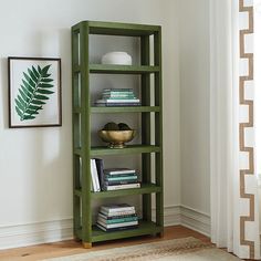 a green bookcase with books on it in a room next to a window and rug